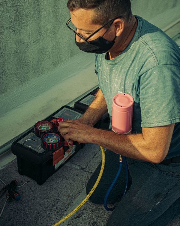Technician using refrigerant gauges on an AC unit