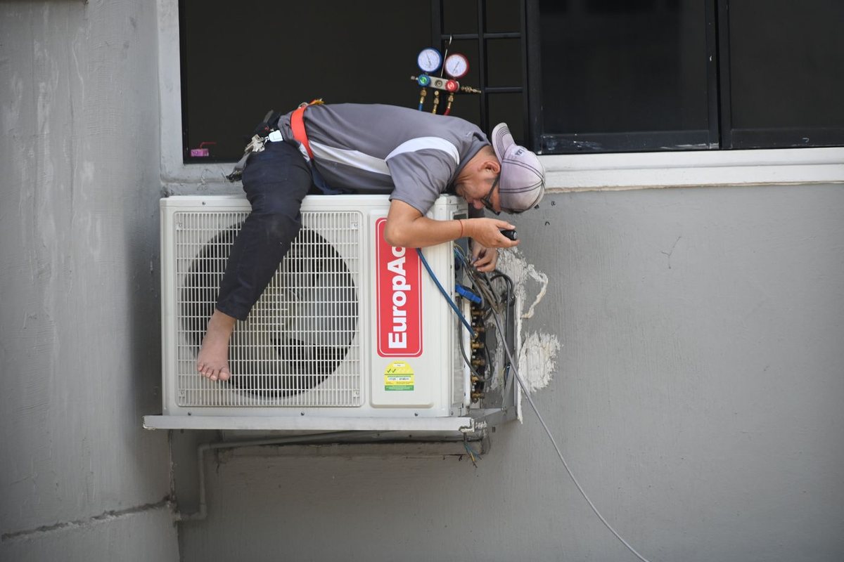 HVAC technician installing and connecting an outdoor AC condenser unit